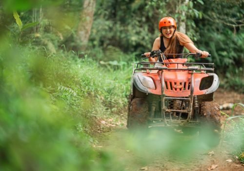 beautiful asian woman riding the atv happily through the atv arena spending her holiday