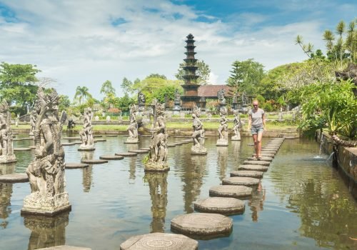 Happy tourist at Tirtagangga water palace with fountains  and ponds on Bali, Indonesia