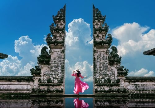 Young woman standing in temple gates at Lempuyang Luhur temple in Bali, Indonesia. Vintage tone.